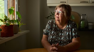 Ihminen istuu pöydän ääressä ja katsoo ikkunasta ulos.